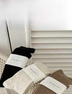 Three pairs of ribbed knit crew socks in black, beige, and dark brown colors