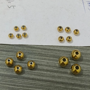Macro detail of various sizes of golden stainless steel hollow beads for DIY jewelry making