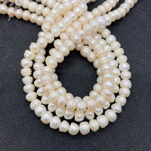Macro detail of high-luster white button-shaped natural freshwater pearl strands for jewelry