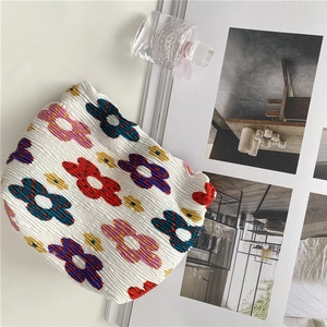 Detailed view of white pleated floral makeup bag with colorful polka dots on aesthetic background