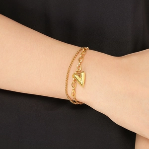 Detailed shot of double-layered gold heart bracelet with textured link chains on wrist