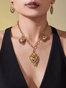 Parure de bijoux cœur doré avec perles et pompons portée par un mannequin