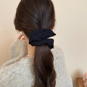 Detail of black double-layered hollow lace scrunchie on brown hair with elegant texture