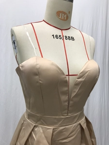 Detail van een champagne satijnen jurk met diepe V-hals en een geplooide maxi rok