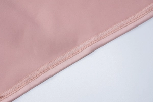 Dettaglio ravvicinato della cucitura overlock sul bordo di un abito in tessuto rosa