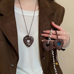 Detailed view of heart pendants with horse motifs and pearl beaded chain necklace