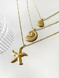 Detailed view of three ocean-themed gold starfish and shell pendant necklaces