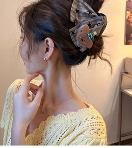 Detail of cute brown striped bow hair claw clip with bear decor on a model's head