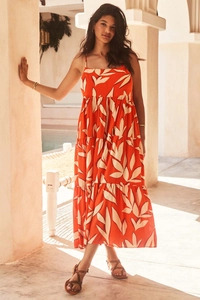 Detailed close-up of vibrant orange-red maxi dress with white leaf print and tiered layers