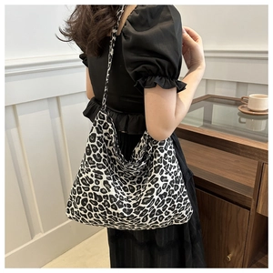 Close-up of leopard print crossbody bag worn by a model in a minimalist interior setting