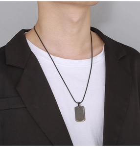 Man wearing a black military dog tag necklace with a sleek polished snake chain