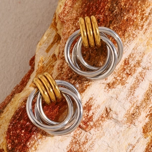 Détail macro de boucles d'oreilles bicolores dorées et argentées sur roche naturelle