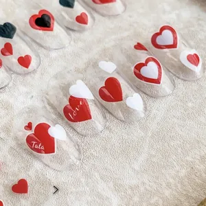 Chic long oval press-on nails with layered red, black and white heart motifs on plush fabric