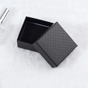 Boîte à bijoux carrée noire avec couvercle à losanges sur surface en peluche blanche