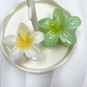 Detail view of white and green plumeria flower hair claws on a jewelry tray