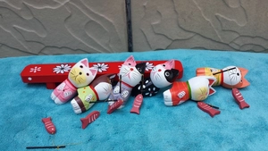 Set mit 6 handgefertigten Angelkatzen-Figuren aus Holz mit rotem Sockel auf blauem Textil