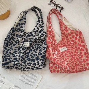 Detail view of leopard print canvas tote bags in grey and pink with brand label on fabric