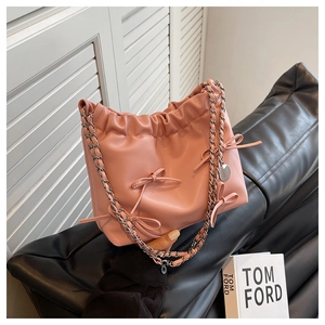 Detailed view of pink leather bucket bag with drawstring closure and bow decoration
