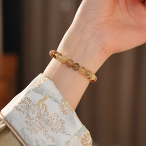 Détail d'un bracelet en quartz rutilé porté au poignet avec un style ethnique chic