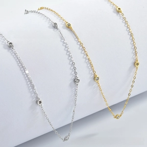Detail view of silver and gold chain necklaces with bezel-set round zircon stones