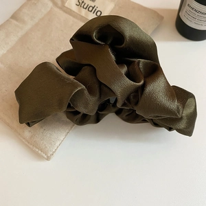 Close-up of olive green satin hair scrunchie with silky texture and elegant glossy finish