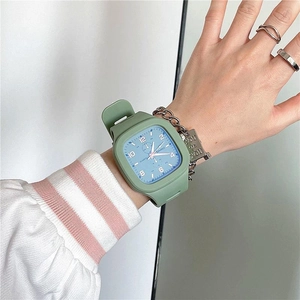 Wrist view of a square quartz watch with a green silicone strap and a matching chain bracelet