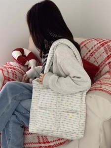 Women's fluffy tote bag with colorful stripes and pockets shown in a cozy lifestyle setting