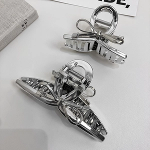 Macro view of two polished silver metal bow hair claws with reflective finish