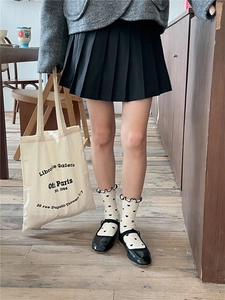 Detail of white ruffle socks with heart patterns worn with black Mary Jane shoes