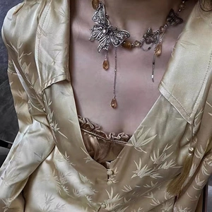 Detail of vintage silver butterfly necklace with amber teardrop tassels and layered chains