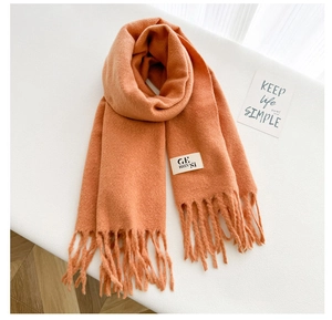 Detail of coral orange wool scarf with soft knit texture and long tassel fringe