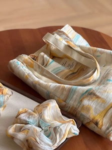 Detail of artistic marble pattern fabric bag and matching scrunchie on wood table