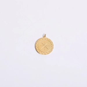 Macro shot of gold-plated celestial tarot pendant with starburst engraving and diamond edges