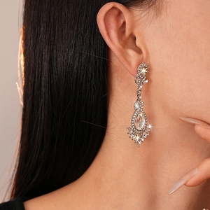 Close-up of sparkling flower teardrop earrings with crystals worn by a model