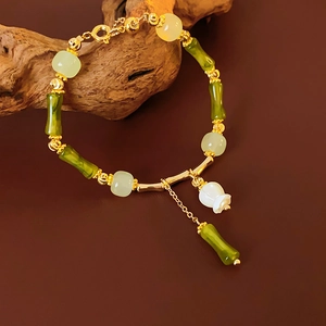 Détail du bracelet style bambou avec perles de jade vert et breloque fleur blanche