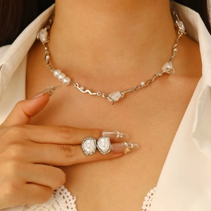 Detail of baroque pearl necklace and matching earrings on a model in silver finish