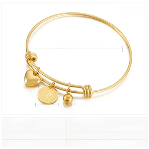 Detail view of gold stainless steel bangle with coin, heart, and ball pendants