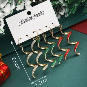 Three pairs of spiral gold metal earrings with glitter accents in a Christmas setting