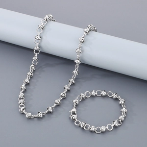 Ensemble collier et bracelet à maillons en acier argenté sur support décoratif