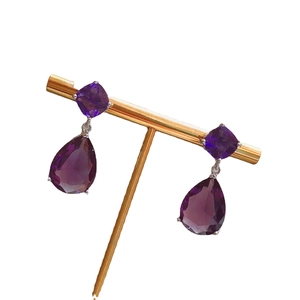 Elegant long teardrop earrings with deep purple crystals on a golden jewelry display