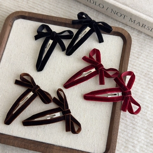 Classic velvet hollow bow hair clips in black, burgundy and brown on a wooden tray