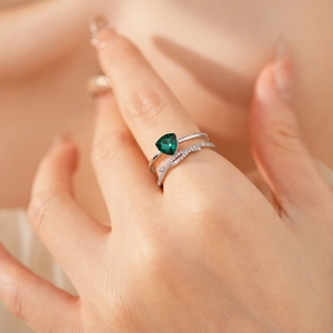 Détail d'une bague croisée argentée avec zircon triangle vert et pierres pavées