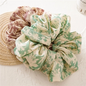 Detail showing two floral fabric scrunchies in green and reddish-brown on a natural background
