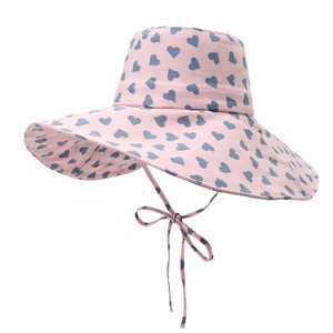 Pink wide brim sun hat with navy blue heart prints and matching windproof bow tie strap