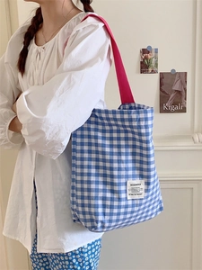 Blue and white checkered canvas tote bag with pink straps shown on female model