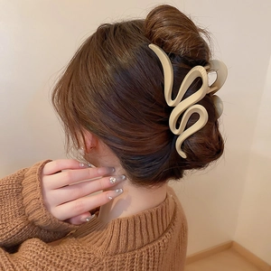 Side view of wavy beige acrylic claw clip styling a low bun on brown hair in soft light