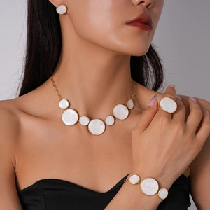Détail d'un ensemble collier et boucles d'oreilles doré avec incrustations blanches