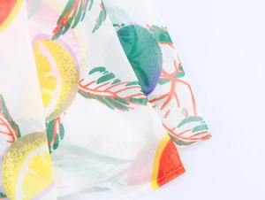 Détail du tissu de robe d'été avec imprimés de citrons éclatants et feuilles vertes