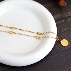 Minimalist gold sunflower smiley face pendant necklace on a white ceramic plate