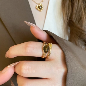 Close-up of gold double-ring set with oval tiger eye and yellow stone on hand